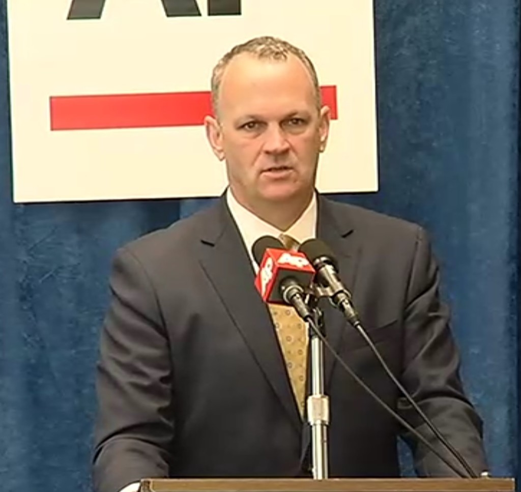 Corcoran behind lectern