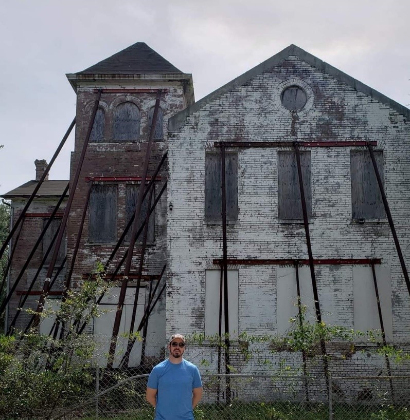 man posing in front of decrepit building